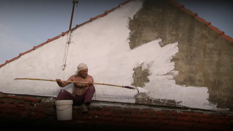 Handwerker bessert eine alte Hauswand mit Putz und Farbe aus